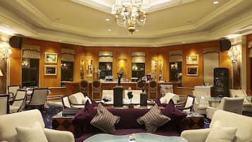 A spacious hotel lobby with a high ceiling, chandeliers, and comfortable seating areas.