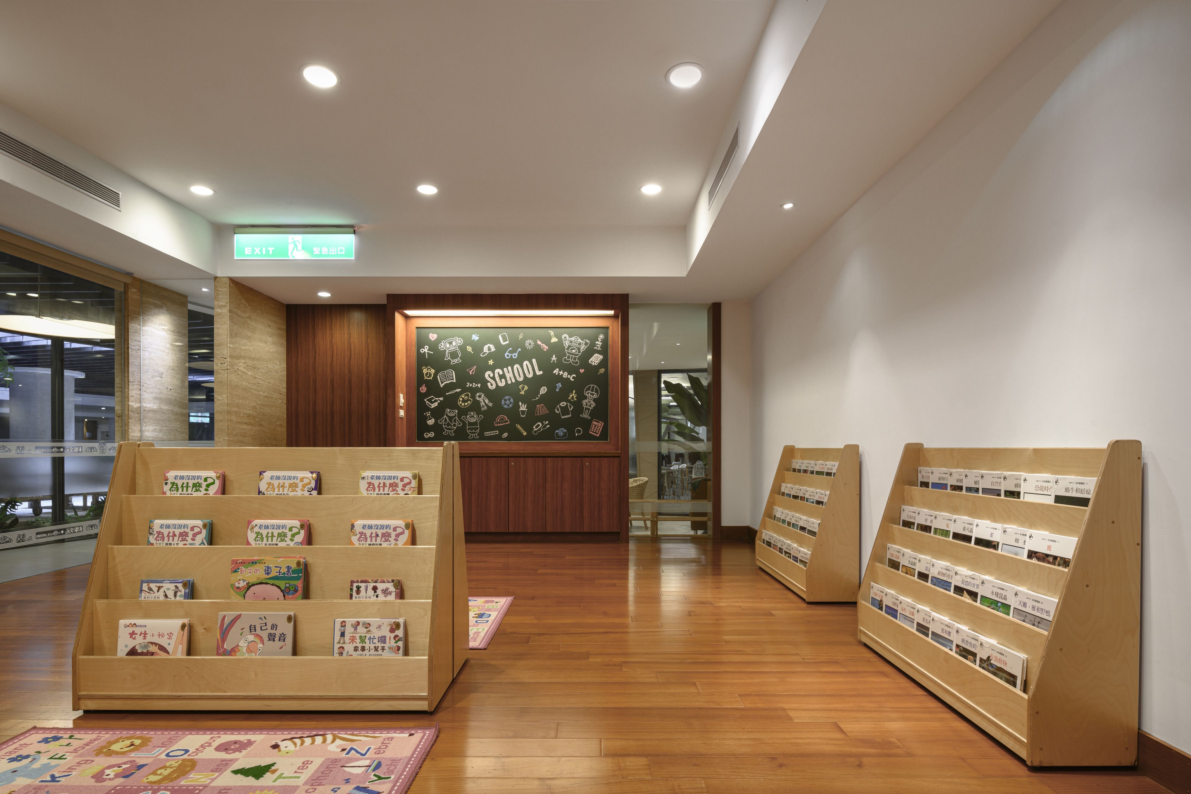 A reception area with wooden flooring, a reception desk, and a chalkboard wall with school-related drawings.