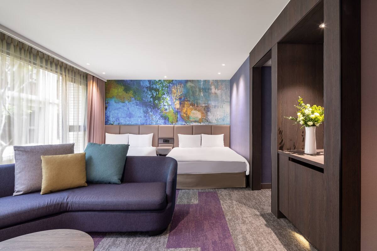 A modern hotel room with a large bed, a sofa, and a desk.
