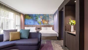 A modern hotel room with a large bed, a sofa, and a desk.