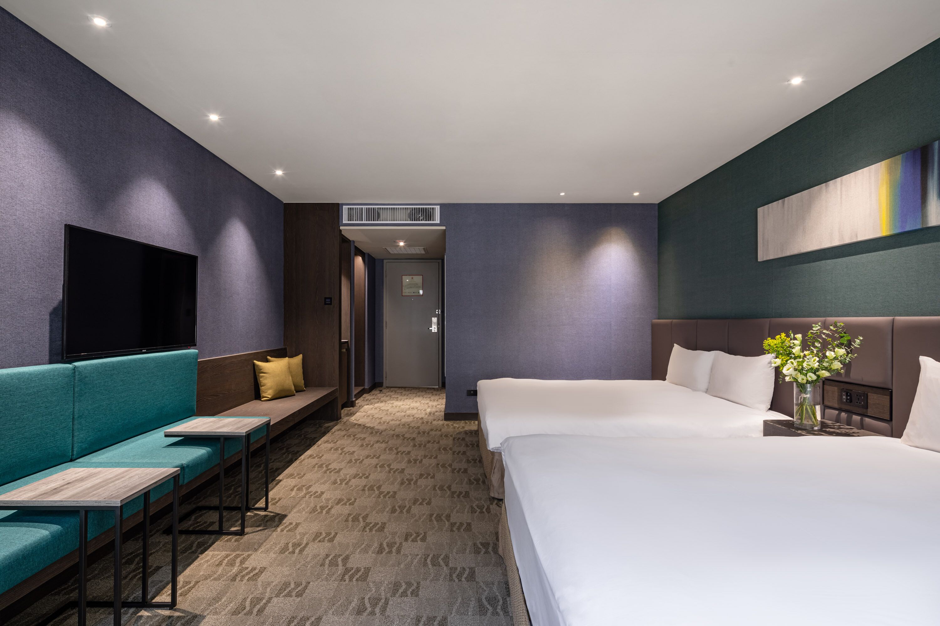 A modern hotel room with a large bed, a sofa, a TV, and a small table.
