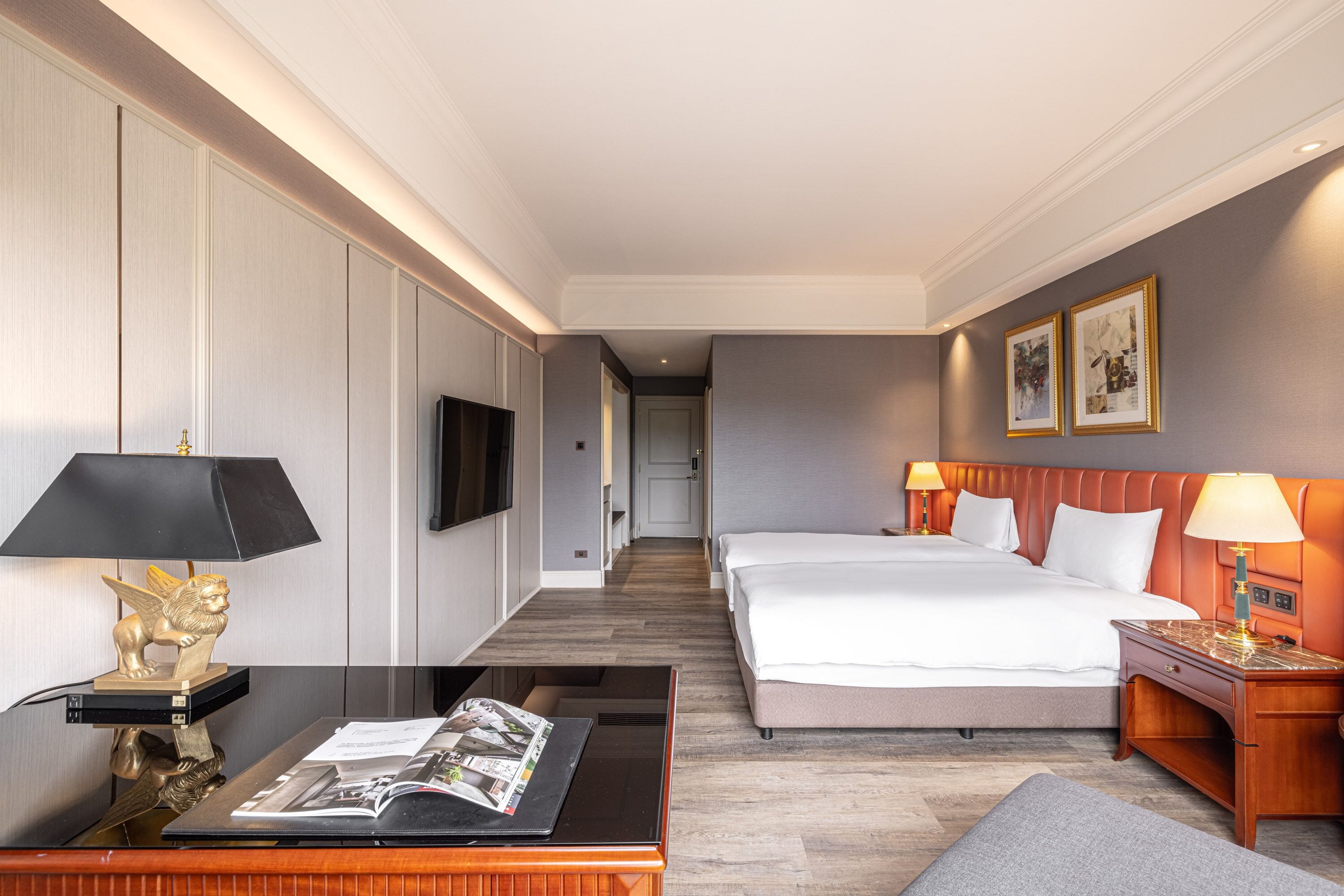 A hotel room with a bed, bedside tables, a TV, and a magazine on a table.