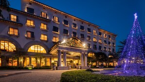 Um hotel com uma entrada imponente, vários andares e uma grande árvore de Natal.