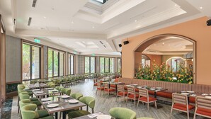 Um restaurante amplo, com pé-direito alto, grandes janelas e diversas opções de assentos, incluindo mesas e cabines.