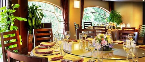 Un comedor con una mesa redonda dispuesta para cuatro personas, rodeada de sillas de madera con asientos acolchados.