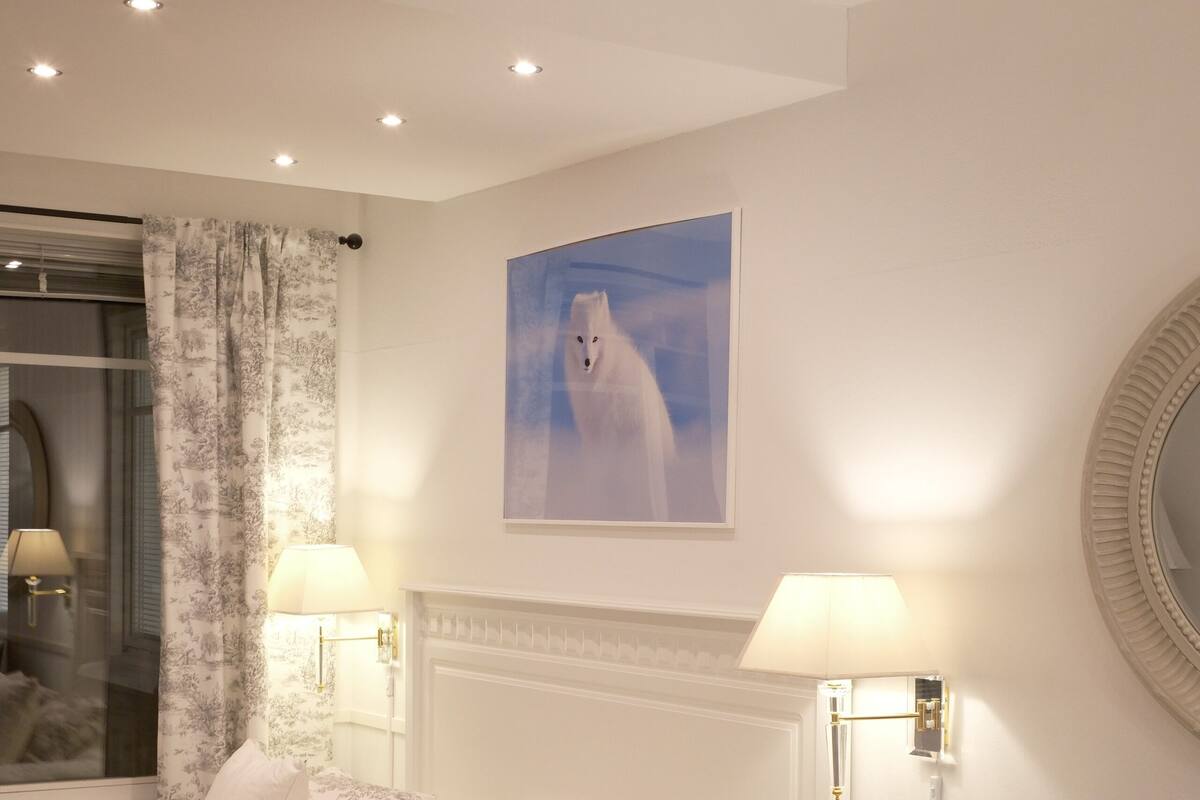 Une chambre à coucher avec un lit, des lampes de chevet, une table de chevet, une chaise, un tableau et un miroir.