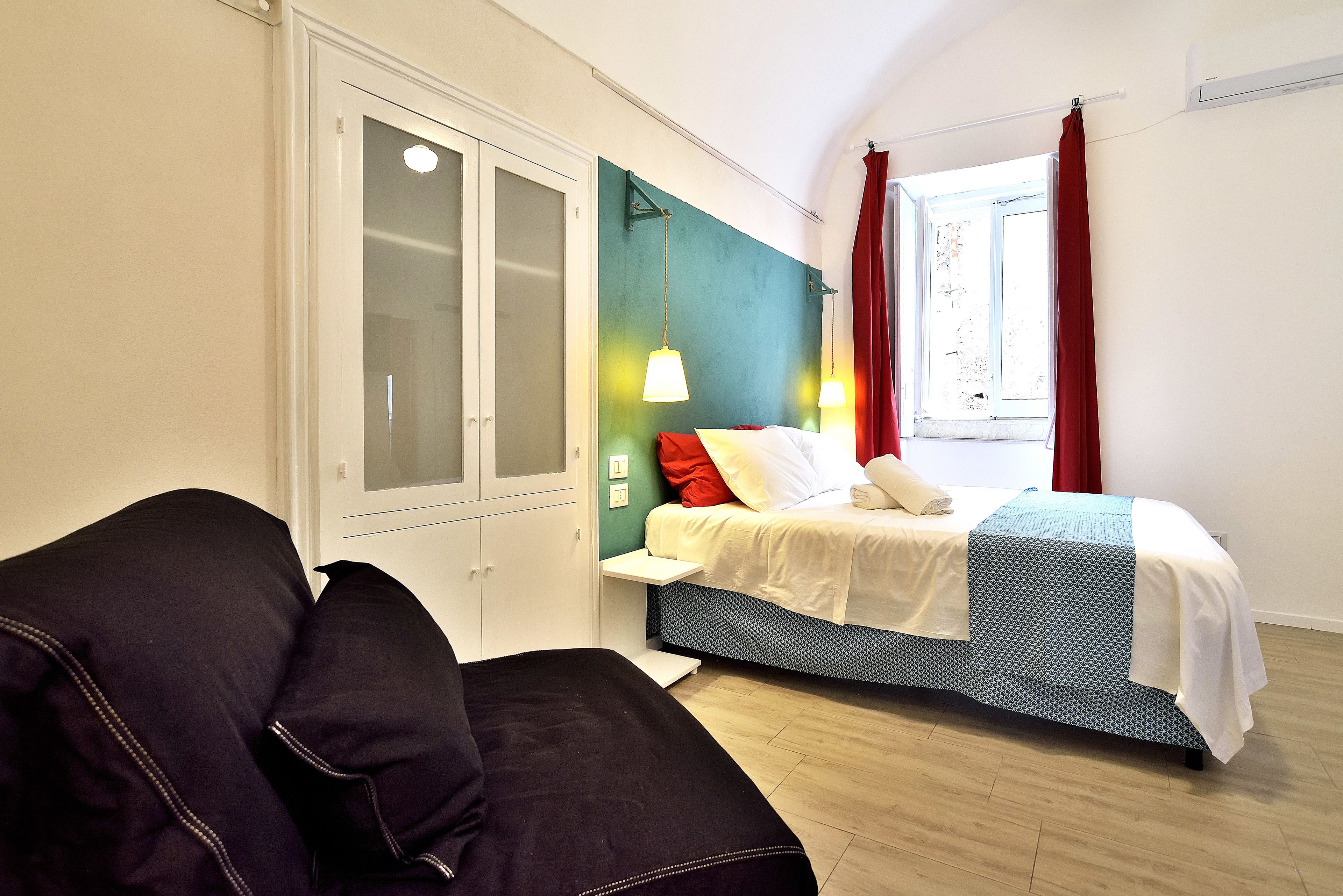 A bedroom with a bed, a wardrobe, a window with curtains, and a bedside table.