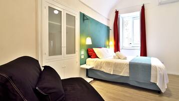 A bedroom with a bed, a wardrobe, a window with curtains, and a bedside table.