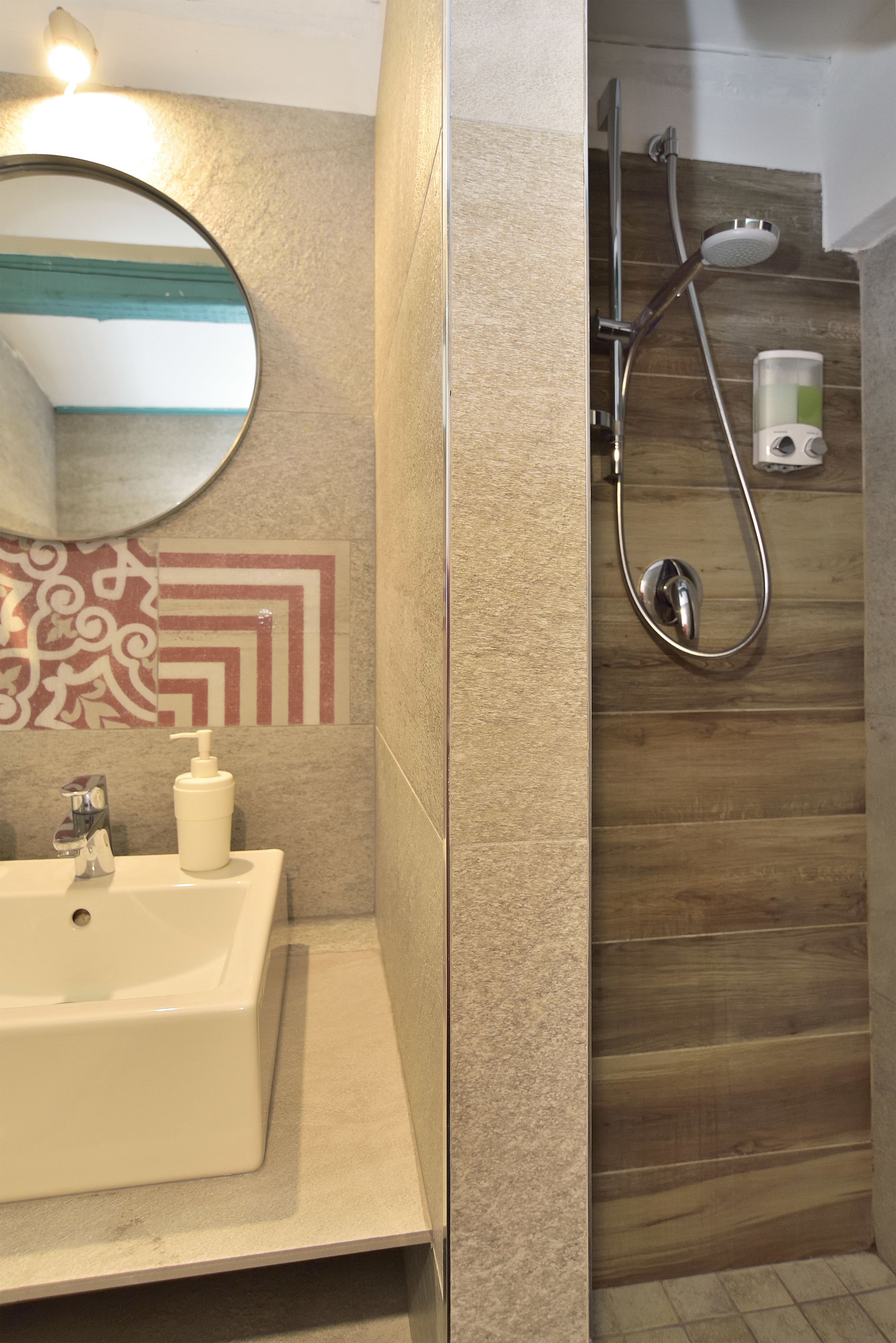 A bathroom with a sink, mirror, shower, and decorative wall tiles.