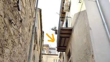 Um beco estreito com uma escadaria que sobe, ladeado por edifícios com canos e varandas à mostra.