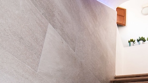 Una escalera con escalones de madera y paredes de piedra gris.