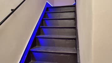 Een trap met blauwe verlichting, leuningen en een wandlamp.