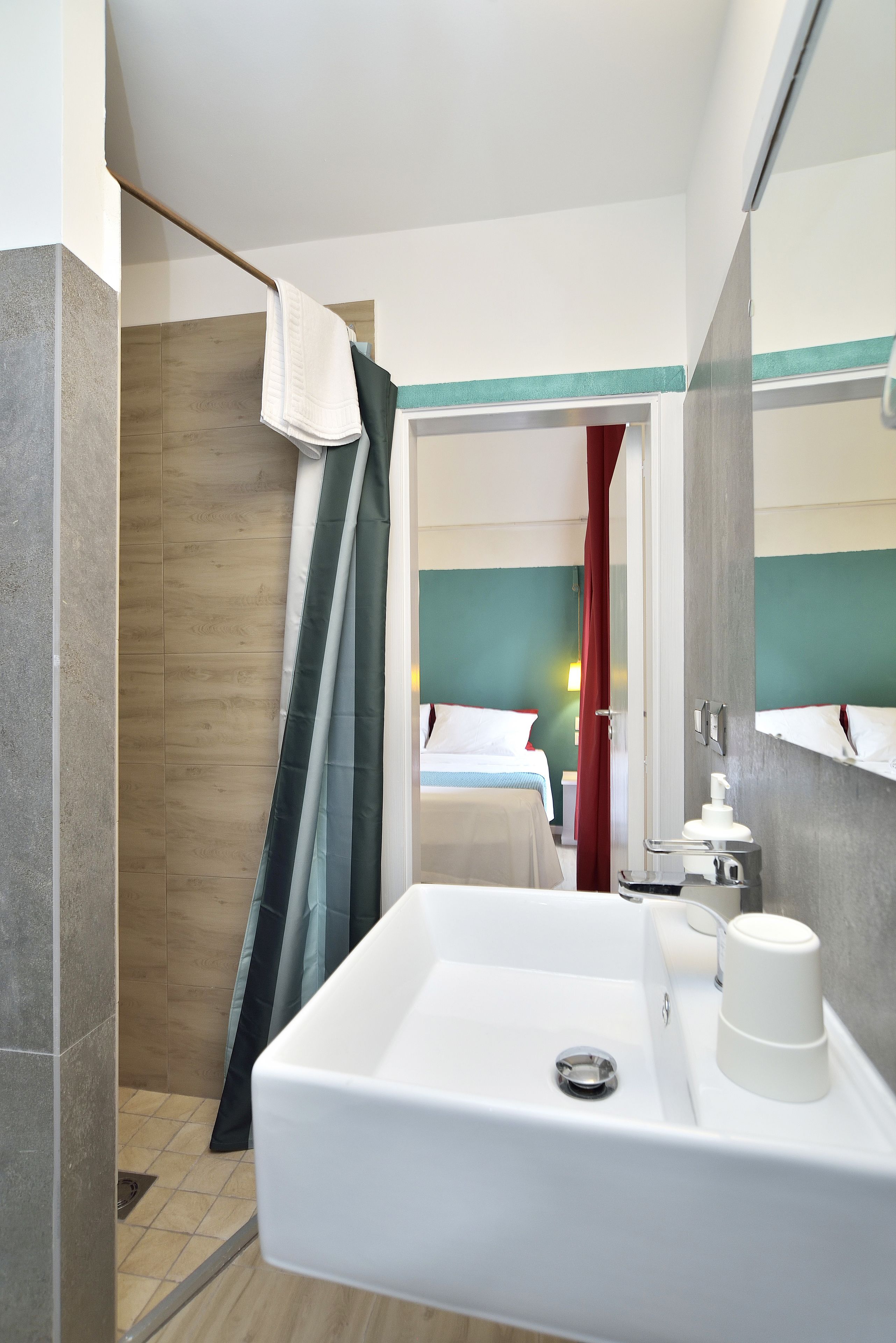 Ein modernes Badezimmer mit einem weißen Waschbecken, einer Duschvorhang und einem Spiegel.