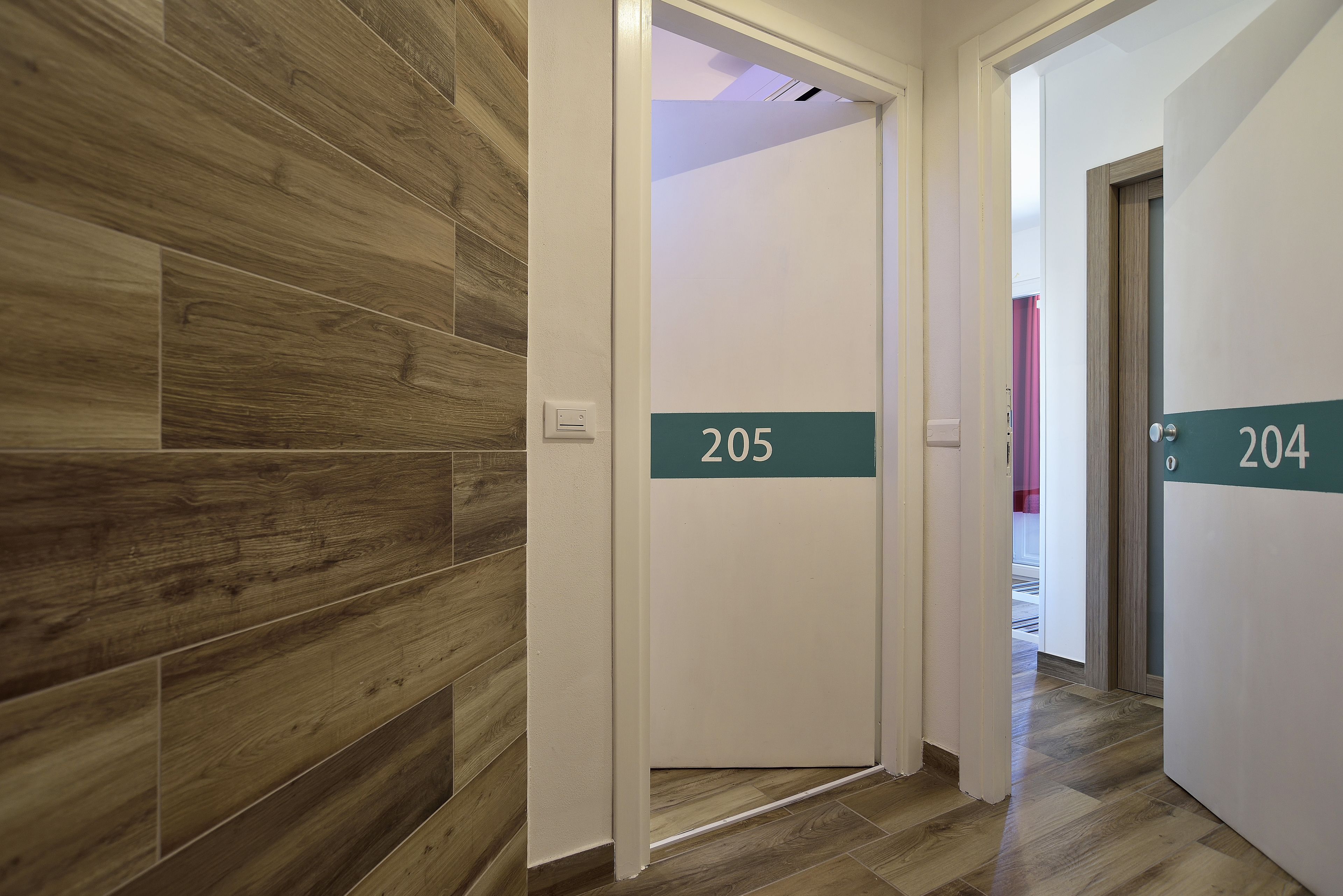 A hallway with wooden flooring and doors numbered 205 and 204.
