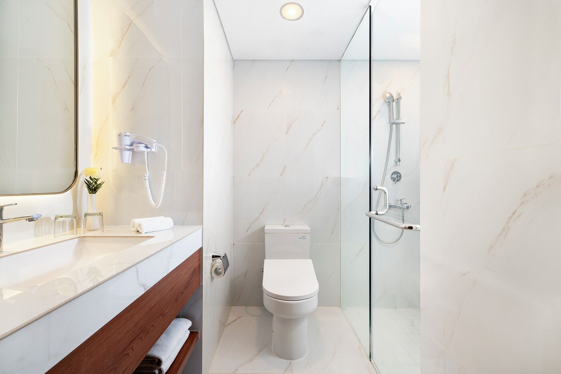 A modern bathroom with a glass-enclosed shower, a toilet, and a vanity with a mirror and a towel rack.