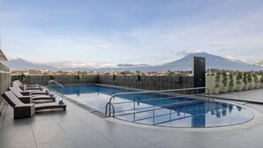 A rooftop swimming pool with lounge chairs and a view of a mountain. - Atria Hotel Malang (Malang)