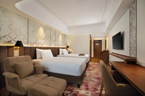 Una habitación de hotel con dos camas, un sofá, un escritorio y un televisor.