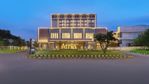 A modern hotel building with a prominent 'Atria' sign, multiple floors, and a well-maintained lawn. - Atria Hotel Malang (Malang)