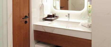 A modern bathroom with a wooden vanity, a large mirror, and a glass shower enclosure.