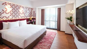 A hotel room with a large bed, a TV, a window with curtains, and a patterned wall.