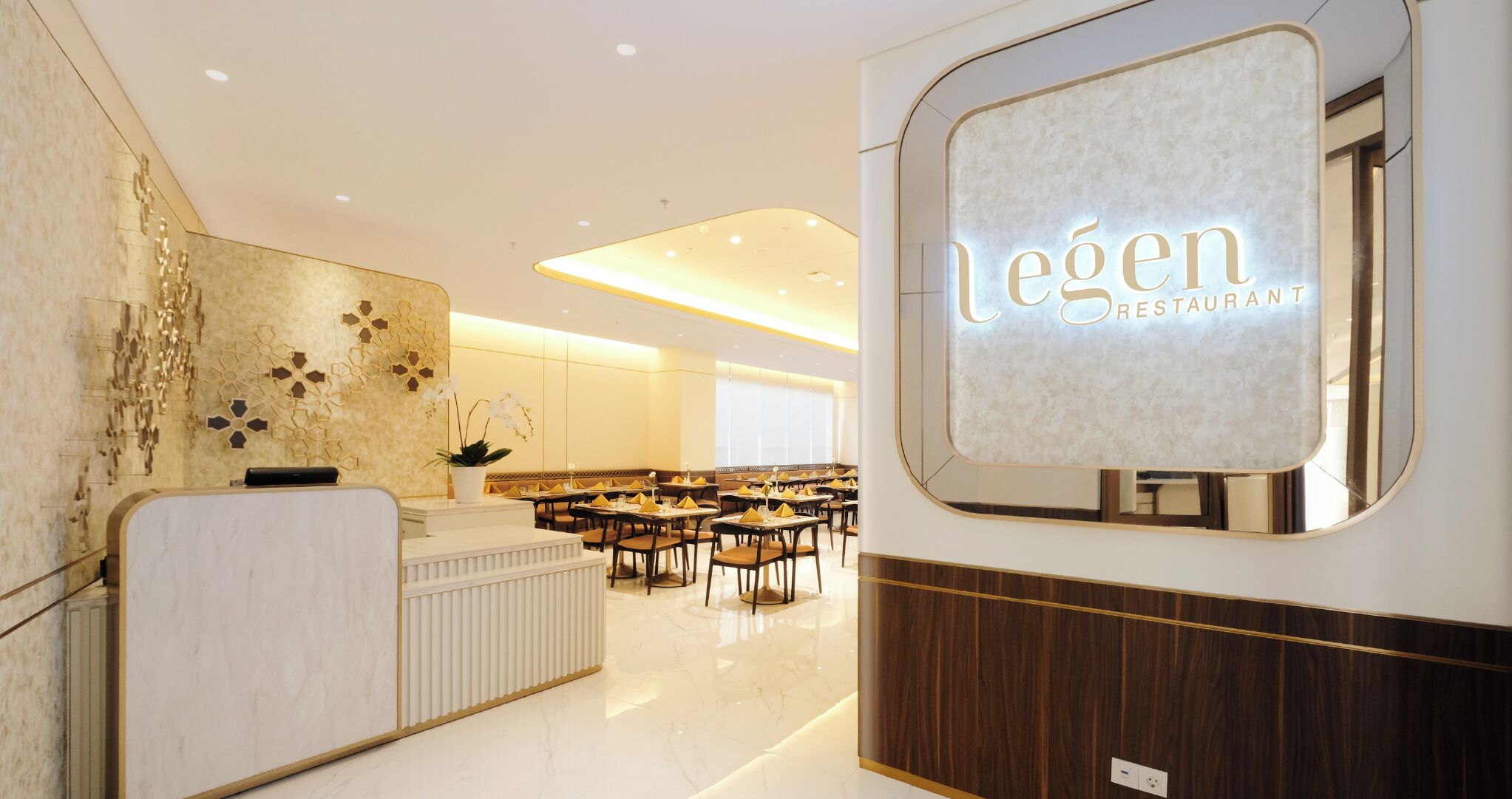 A modern restaurant interior with a reception desk, seating area, and a large illuminated sign reading "legen Restaurant".