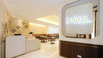 A modern restaurant interior with a reception desk, seating area, and a large illuminated sign reading "legen Restaurant".