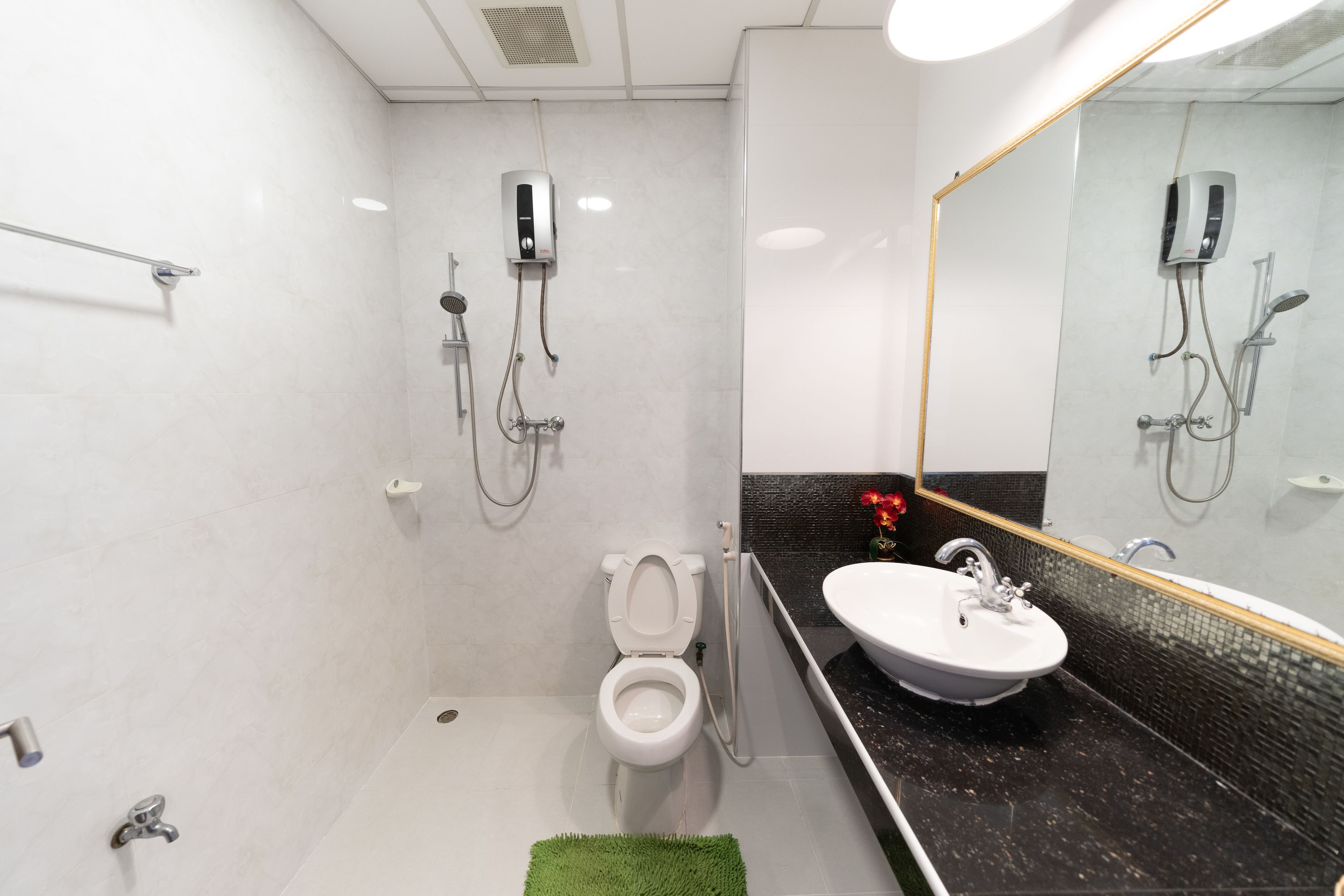 A modern bathroom with a white toilet, a shower area, and a sink with a black countertop.
