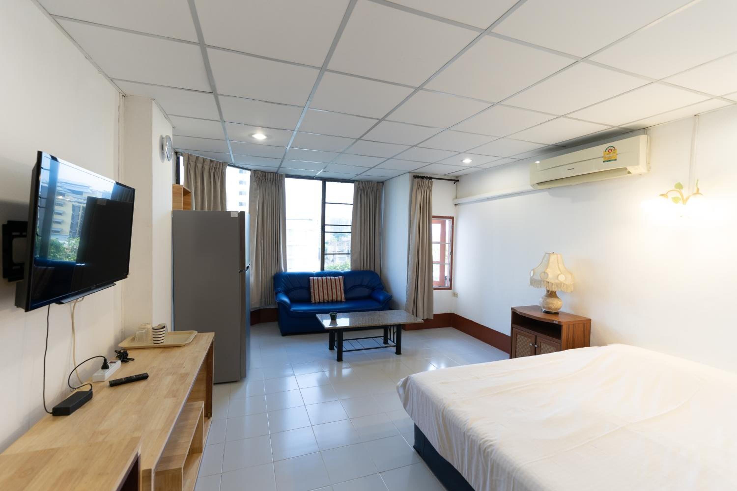 A hotel room with a bed, a TV, a desk, a sofa, and a window.