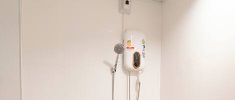 A small, modern bathroom with a toilet, a shower, and a wall-mounted control panel.