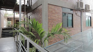 Un edificio con fachada de ladrillo, balcón de vidrio y barandilla metálica.