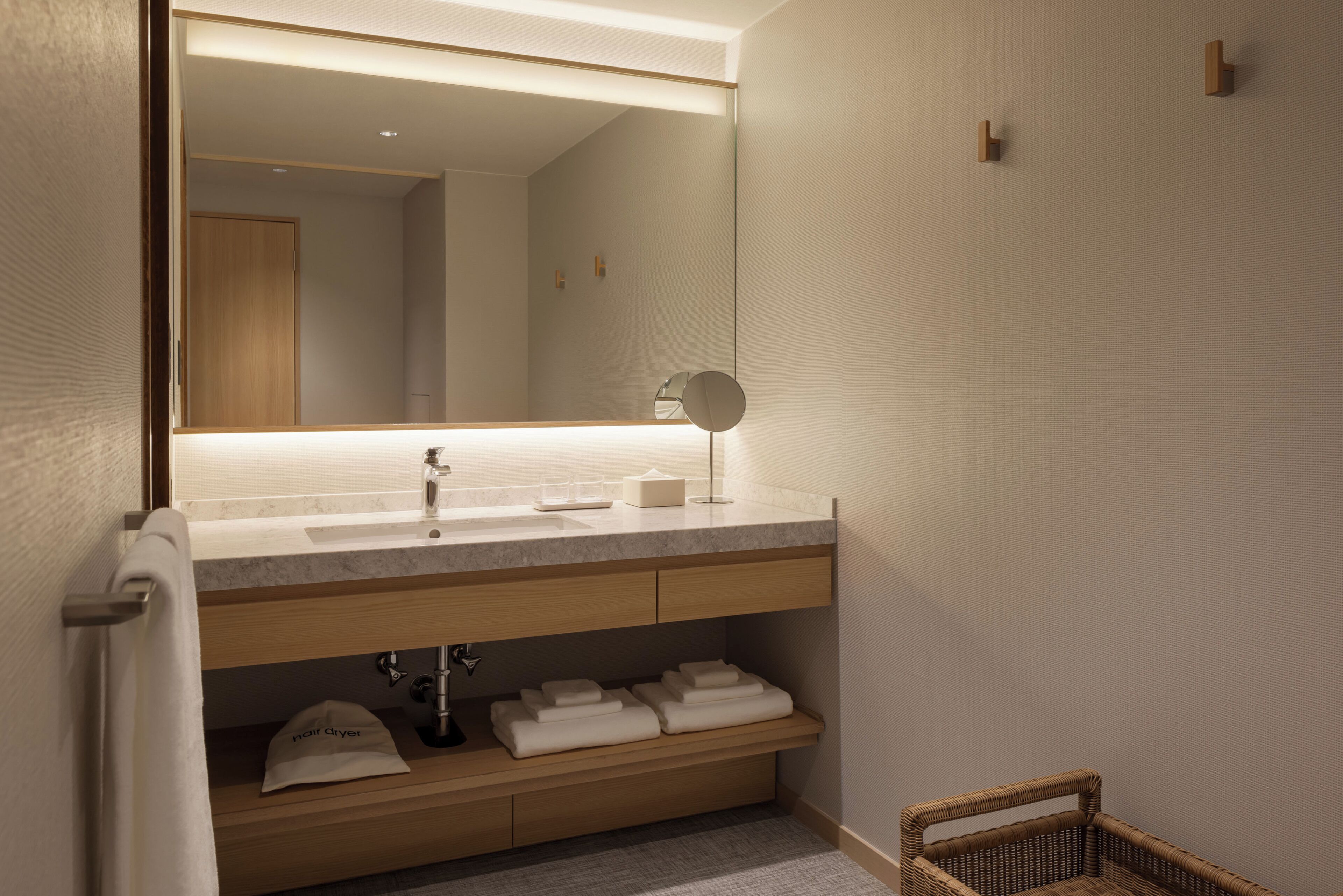 A modern bathroom with a large mirror, a sink, and a towel rack.