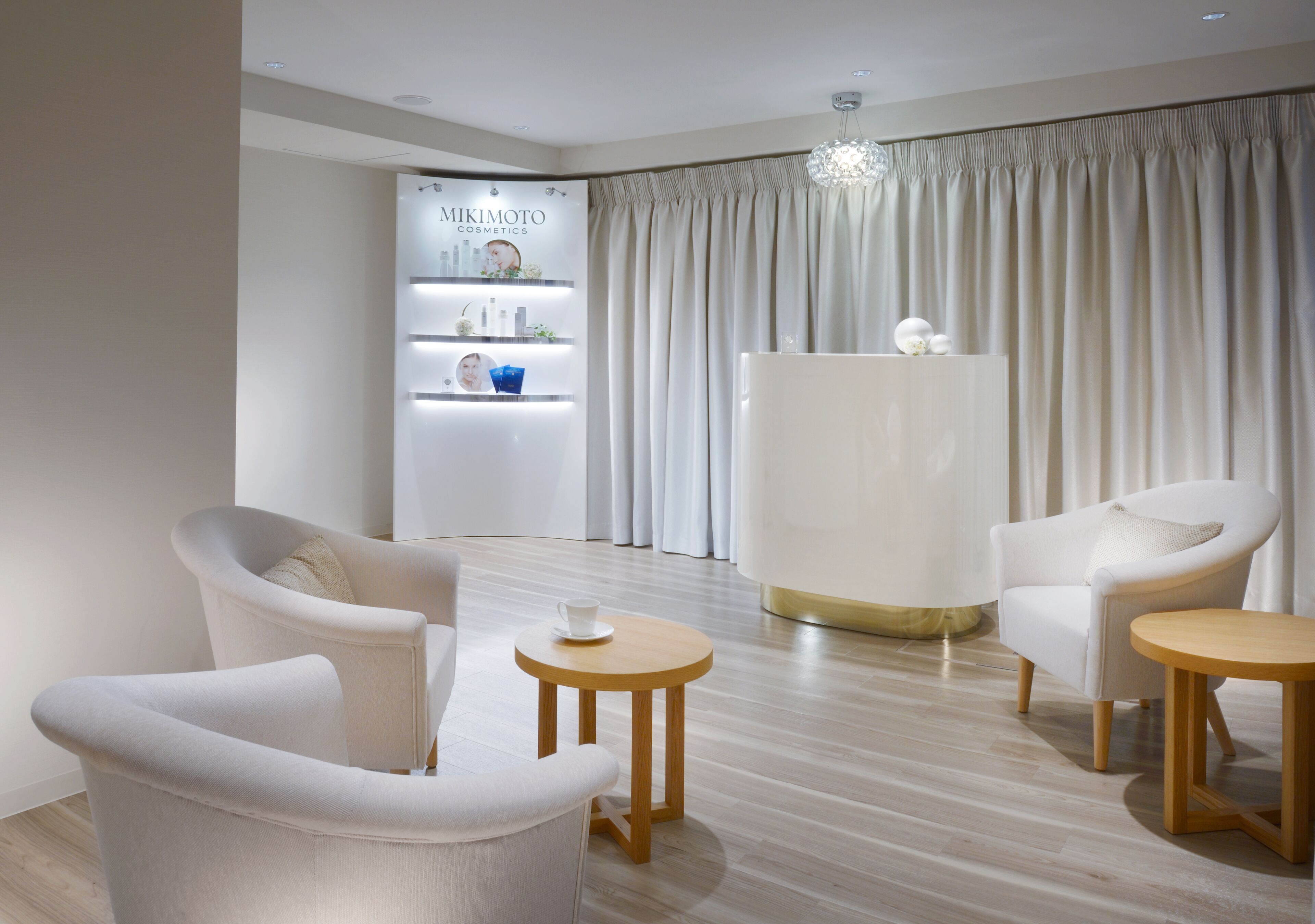 Una sala de estar moderna con un sofá blanco, dos mesas redondas de madera y un mueble blanco grande.