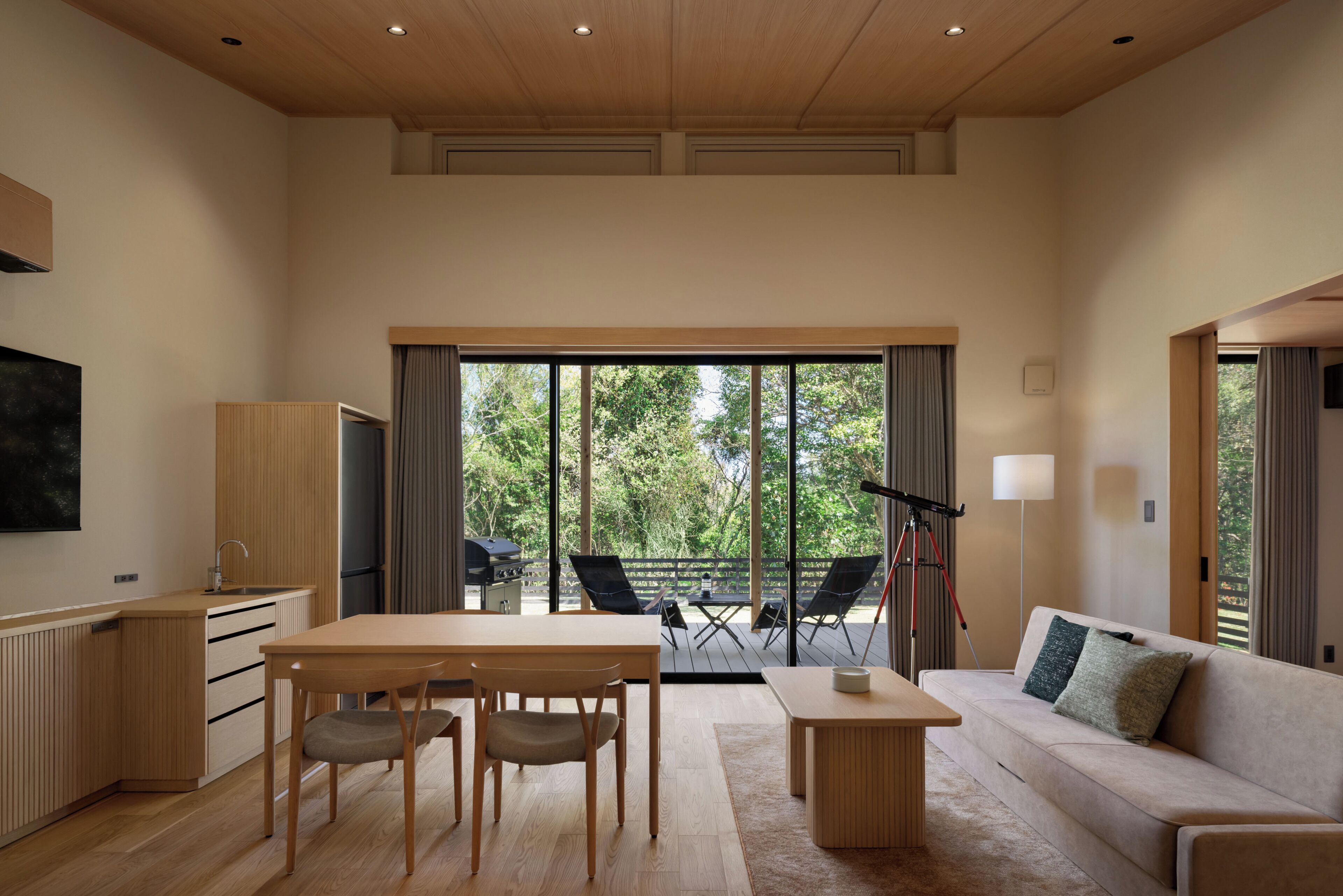 A modern interior with a dining area, sofa, and large sliding glass doors leading to an outdoor deck.