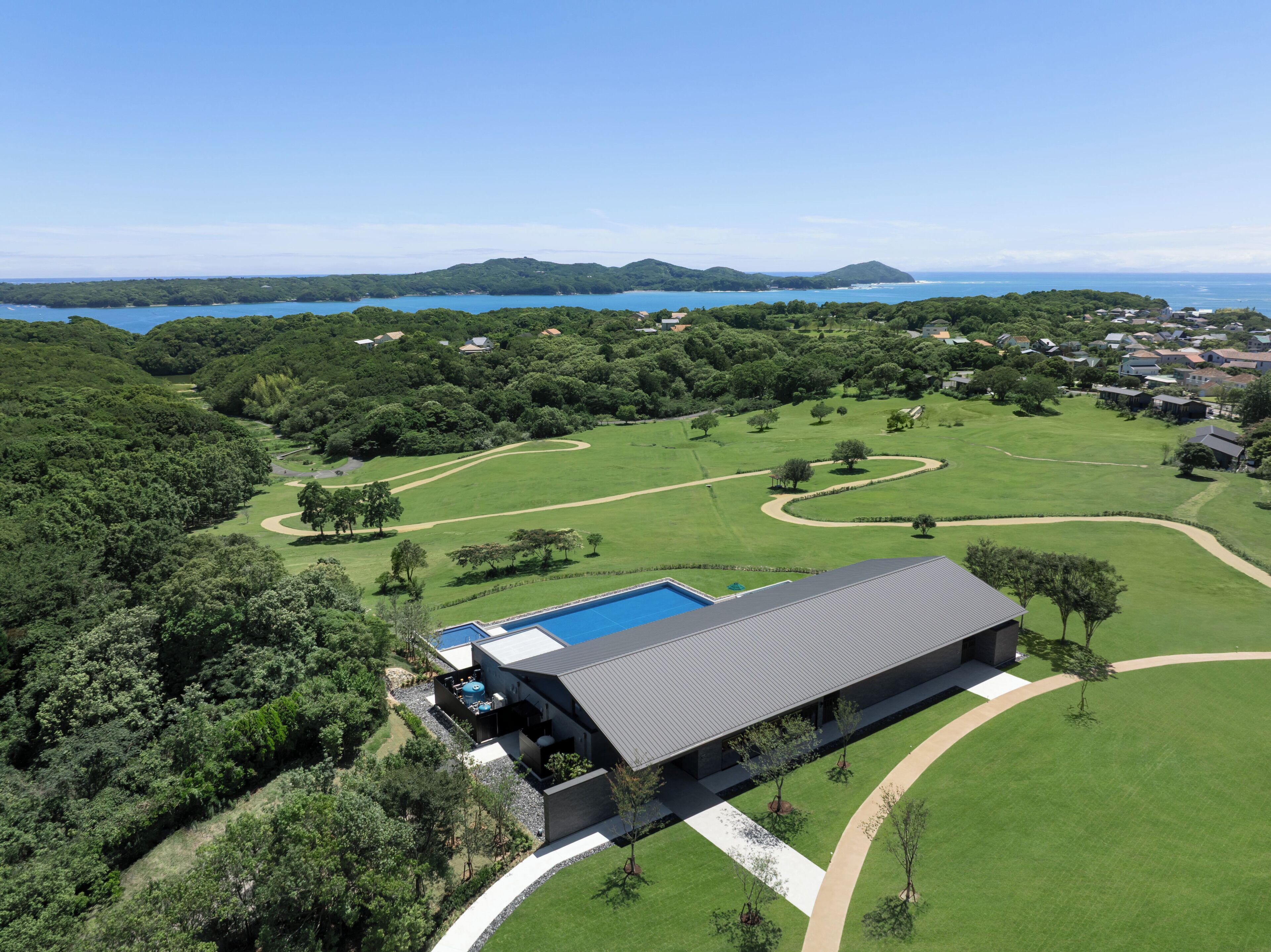 A modern house with a swimming pool, surrounded by lush greenery and a golf course.