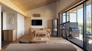 A modern interior with a dining area, a flat-screen TV, and a view of the outdoors. - Nemu Resort Hotel Nemu (Shima)