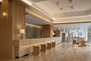 A modern hotel lobby with a reception desk, seating area, and a view into the kitchen. - Nemu Resort Hotel Nemu (Shima)