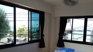 A small room with a bed, a window, and a ceiling fan. - Coffee Island - Hostel (Koh Samui)