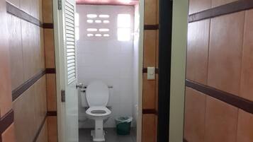 A narrow hallway leading to a bathroom with a toilet and a trash bin.