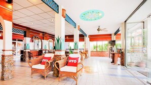 A spacious lobby with wicker chairs, a reception desk, and a large window offering a view of the outdoors. - Chytalay Palace Hotel (Koh Samui)