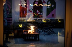 A patio area with a fire feature, outdoor seating, and a mural on the wall.