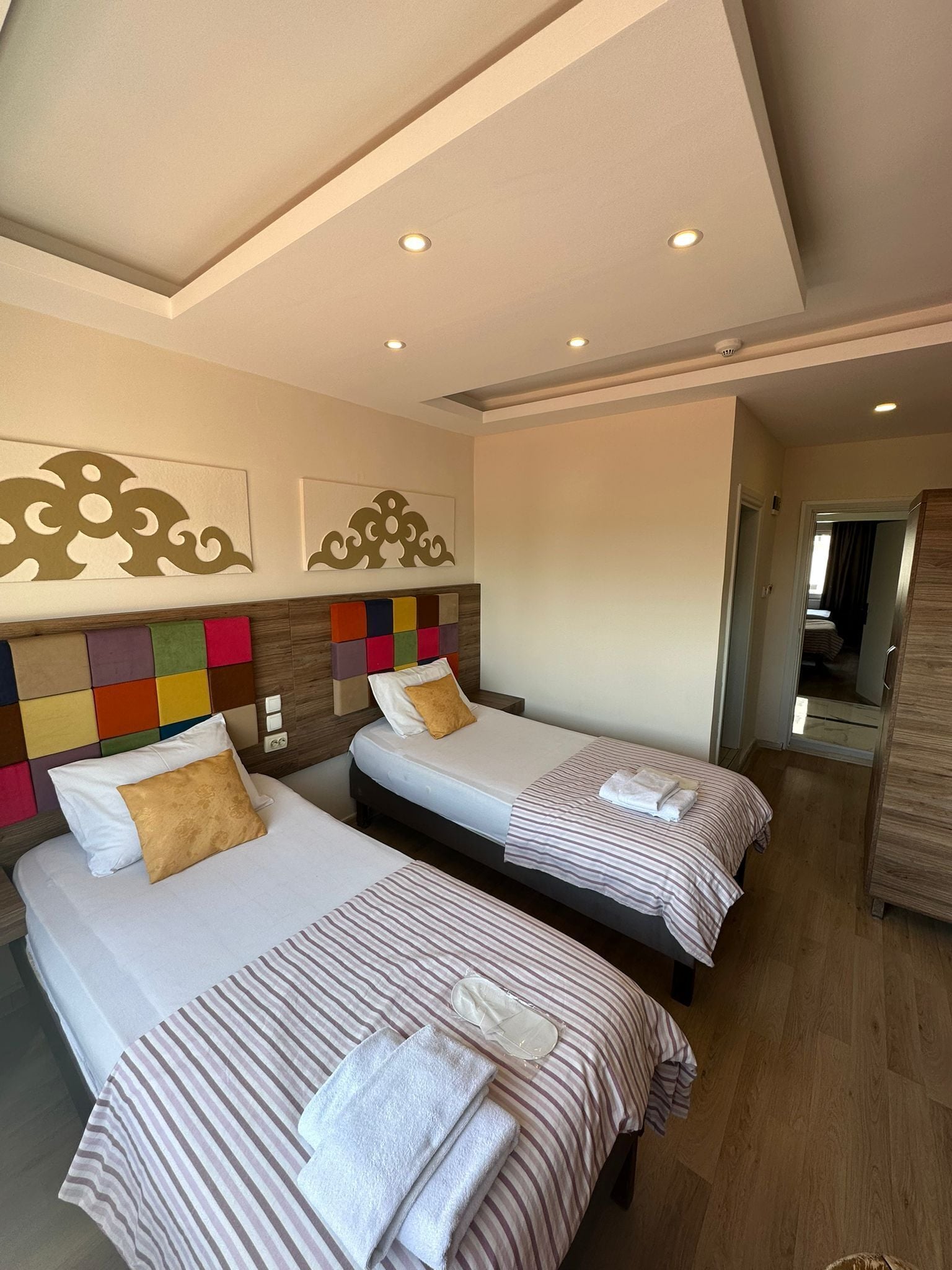 A hotel room with two beds, each with striped bedding and pillows, a wooden headboard, and a wall-mounted artwork.