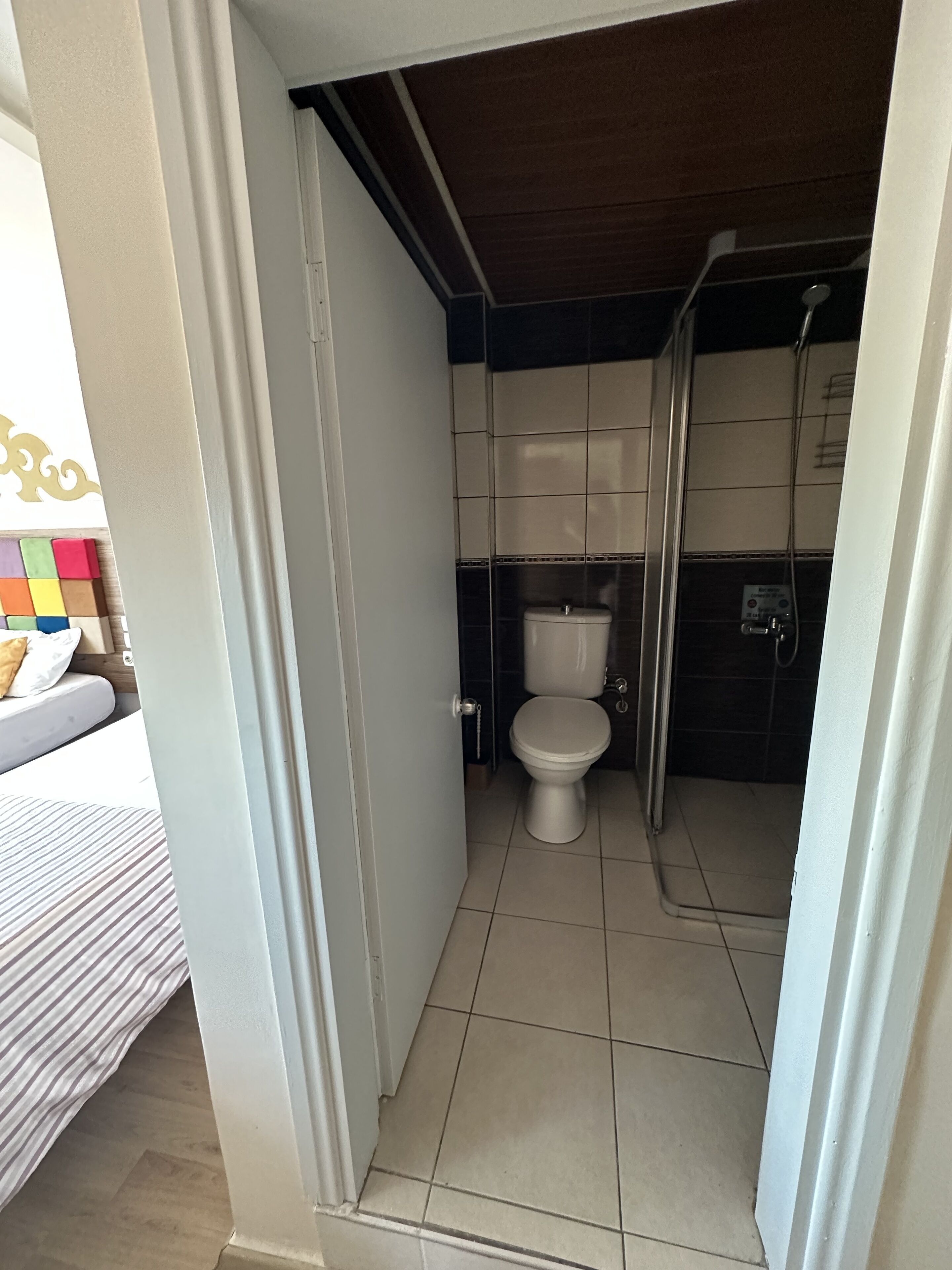 Een kleine badkamer met toilet, douche en betegelde vloer.