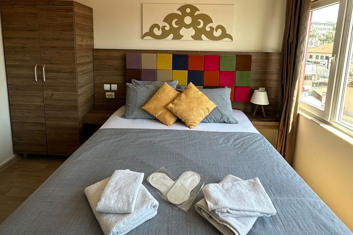Een moderne hotelkamer met een groot bed, een houten garderobe en een kleurrijke wandversiering.