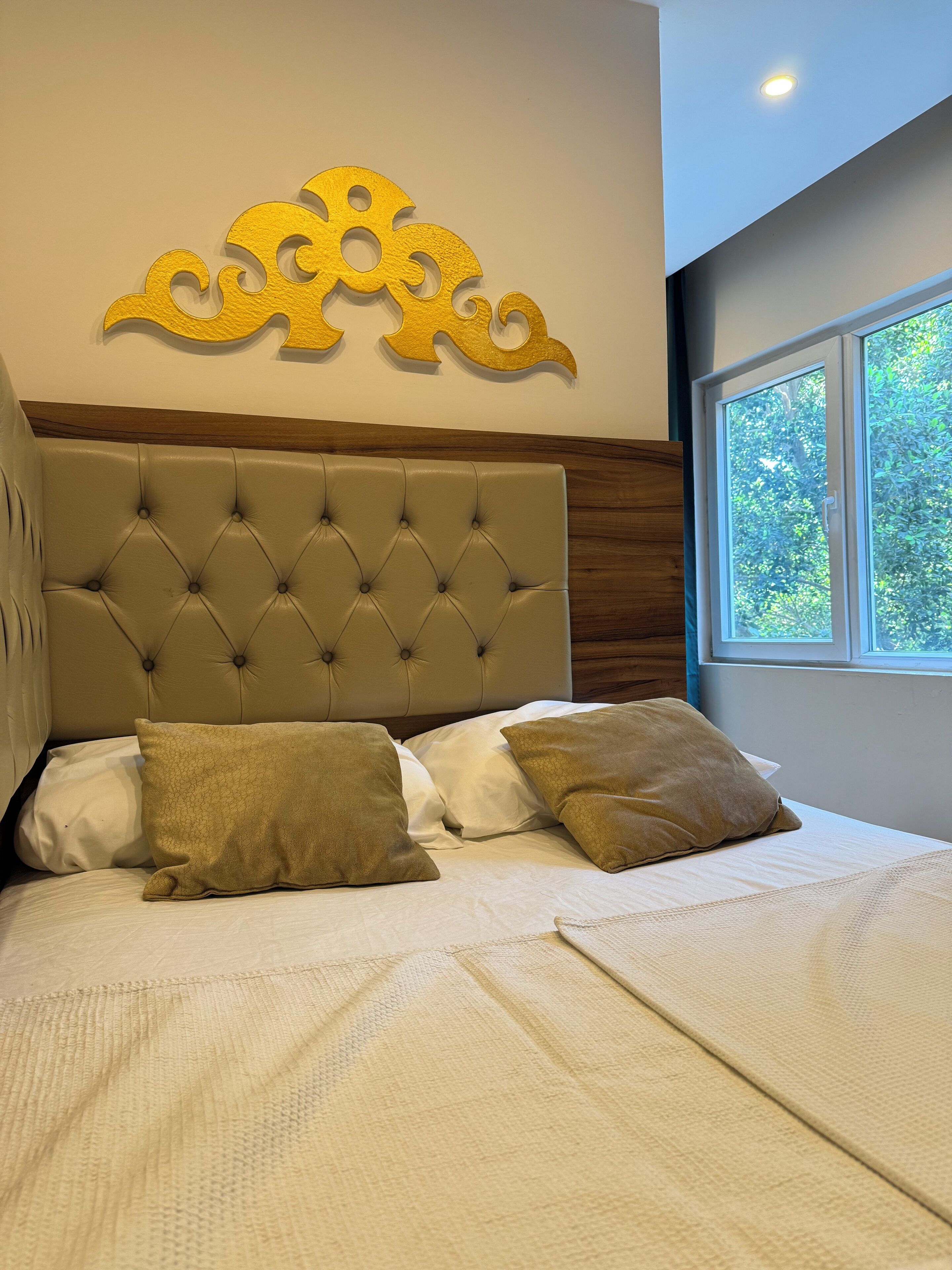 A neatly made bed with a tufted headboard, two pillows, and a decorative wall piece above it.