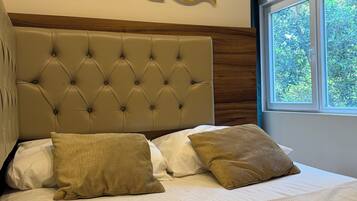 A neatly made bed with a tufted headboard, two pillows, and a decorative wall piece above it.