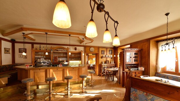 A spacious kitchen with wooden bar stools, a central island, and pendant lighting. - Gasthof Sonne (Imst)
