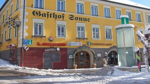 A yellow building with "Sajthof Sonne" written on it, a sign for "L. Roetzer" shop, and a "Tourismusverband" sign. - Gasthof Sonne (Imst)