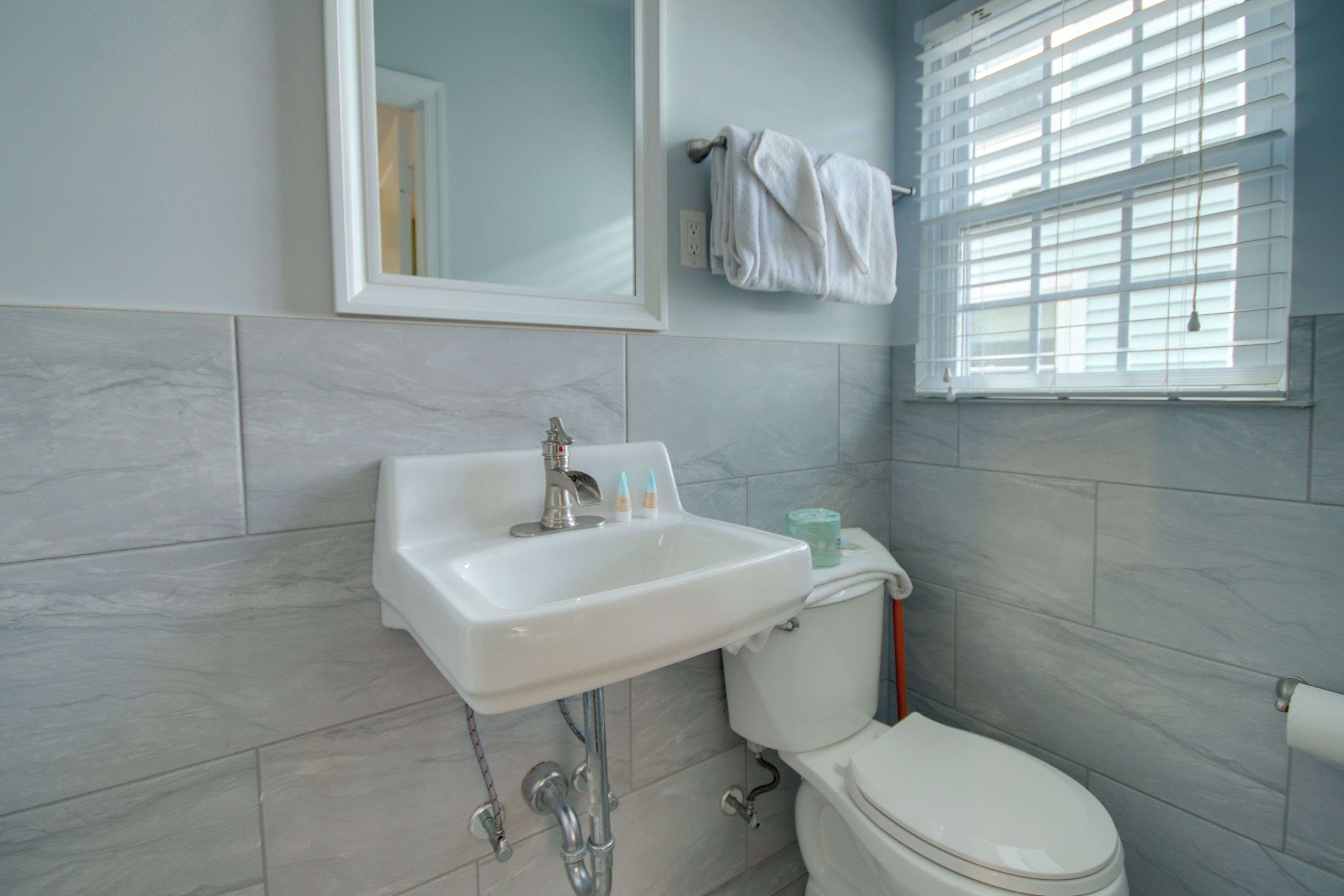 Une salle de bain avec un lavabo blanc, un miroir et des toilettes.