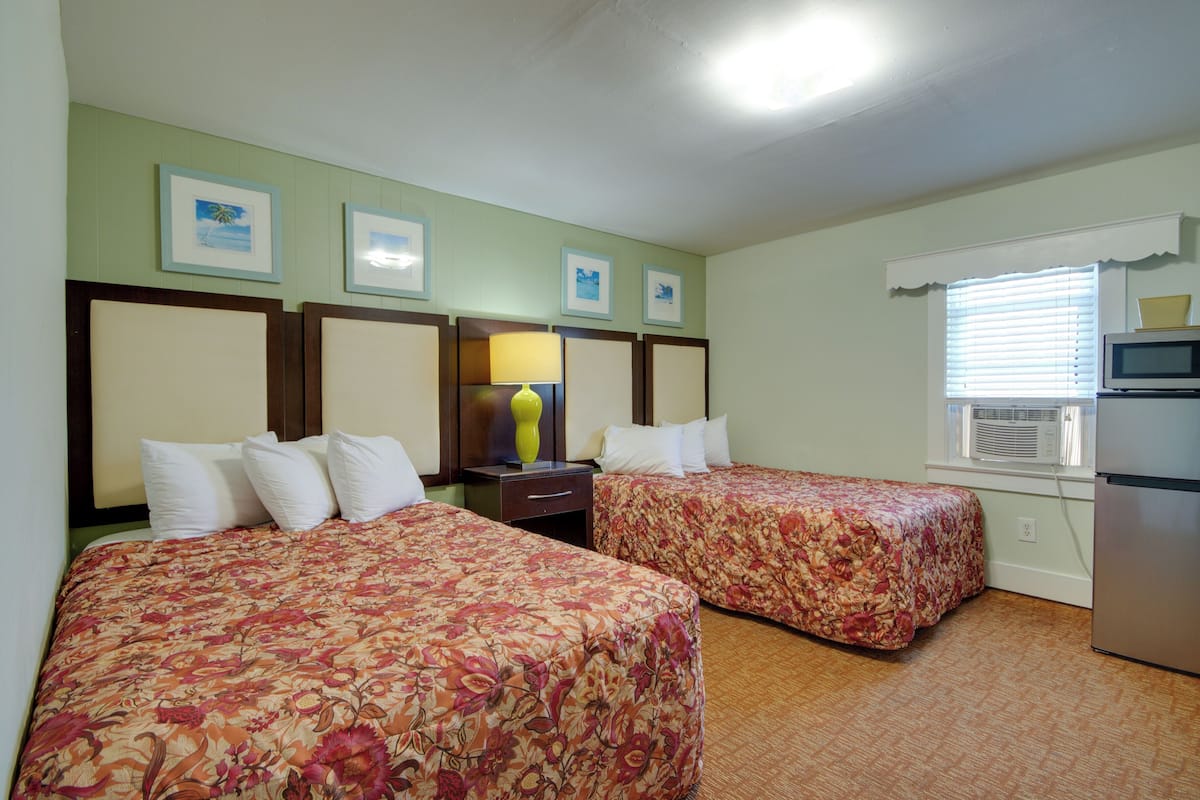 Habitación de hotel con dos camas, microondas y ventana con persianas.