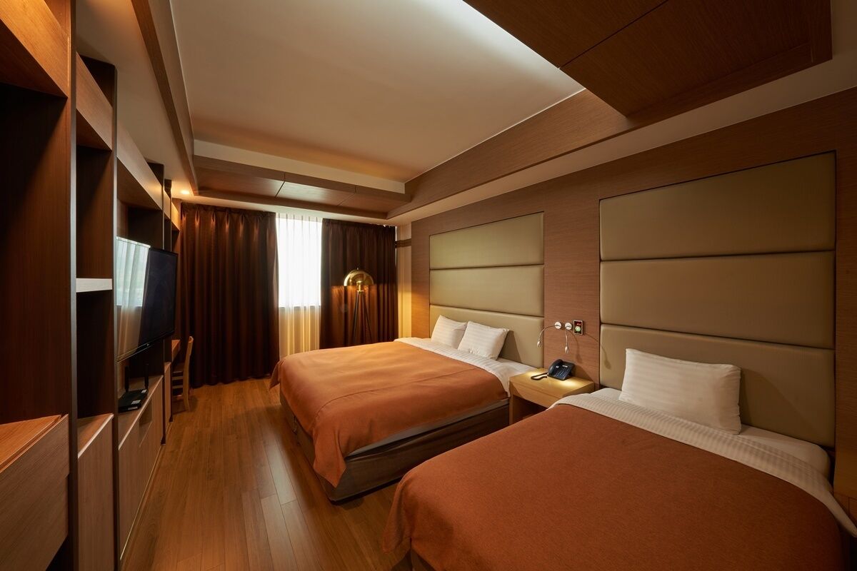 A hotel room with two beds, a TV, and a desk.